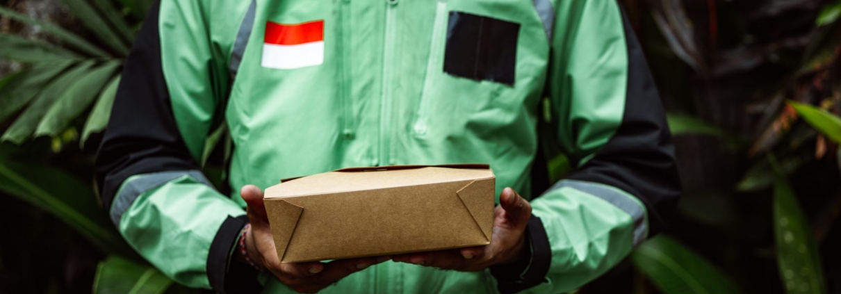 A delivery person in a green jacket holding a box, symbolizing fast delivery service.