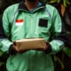 A delivery person in a green jacket holding a box, symbolizing fast delivery service.