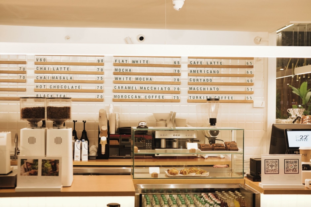 A modern coffee shop interior featuring a menu board and coffee bar setup in warm lighting.