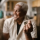A senior man holding a cannabis joint, relaxing indoors with a blurred background.