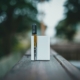 A sleek vape device resting on a wooden surface outdoors in natural light.