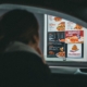 A woman in a car views the menu at a fast food drive-thru, ready to order her meal.