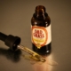 An open CBD tincture bottle with a dropper on a reflective surface.