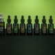 Array of CBD products including oils and serums displayed on a green backdrop.