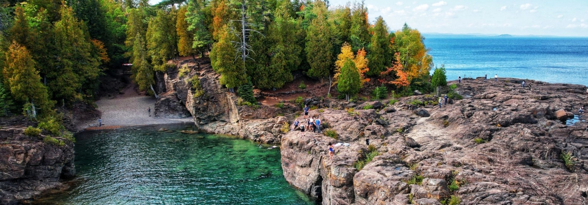 Breathtaking aerial shot of rocky coastline and forest at Presque Isle Park, Marquette, MI.