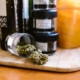 Cannabis buds in glass jars on a wooden board indoors with soft lighting.