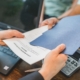 Close-up of hands exchanging real estate documents in an office setting.