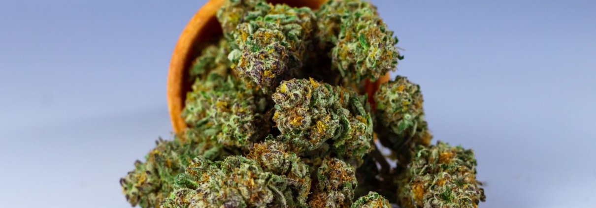 High-quality close-up of cannabis buds in a wooden bowl with a neutral background.