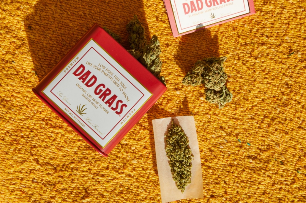 Organic CBD hemp flower package 'Dad Grass' on a colorful rug.