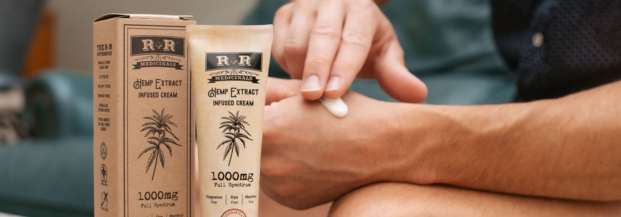 Person applying hemp-infused cream with packaging visible, promoting skincare benefits.