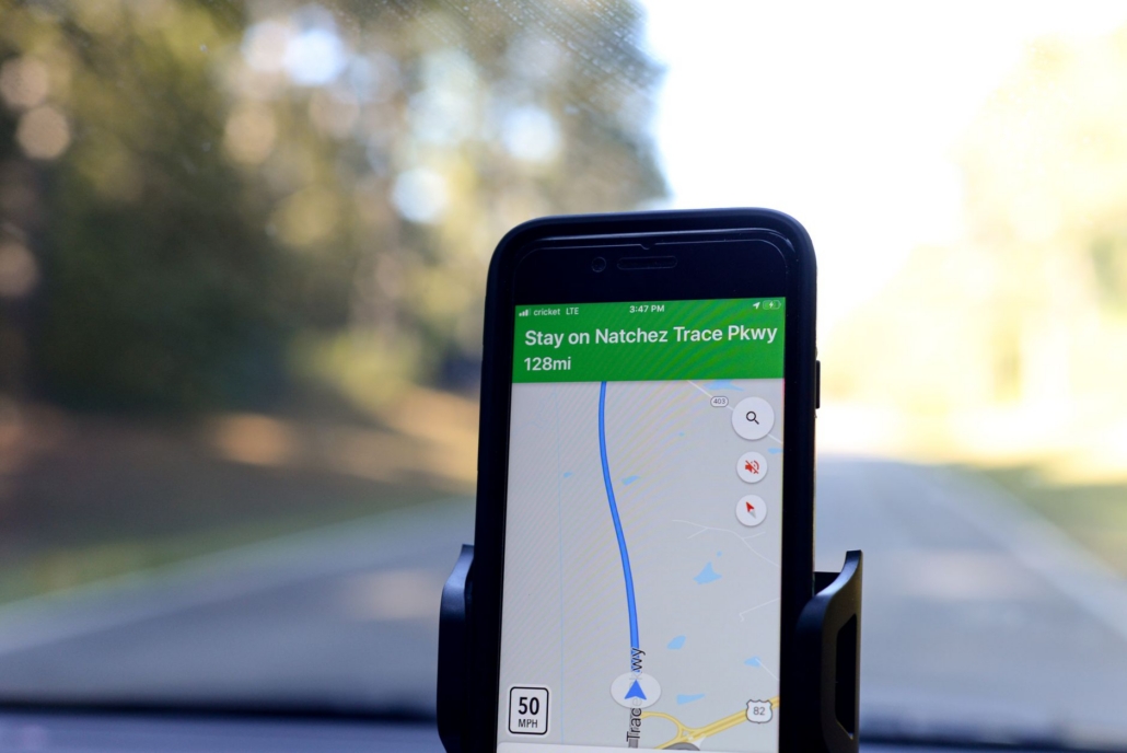Smartphone displaying GPS navigation route on Natchez Trace Parkway inside a car.
