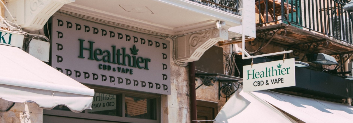 Street view of a CBD and vape store with decorative balcony in an urban area.