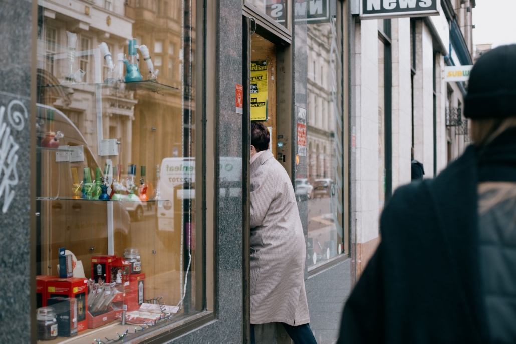 Street view of a person entering a shop in Glasgow, Scotland, showcasing a vibrant display window.