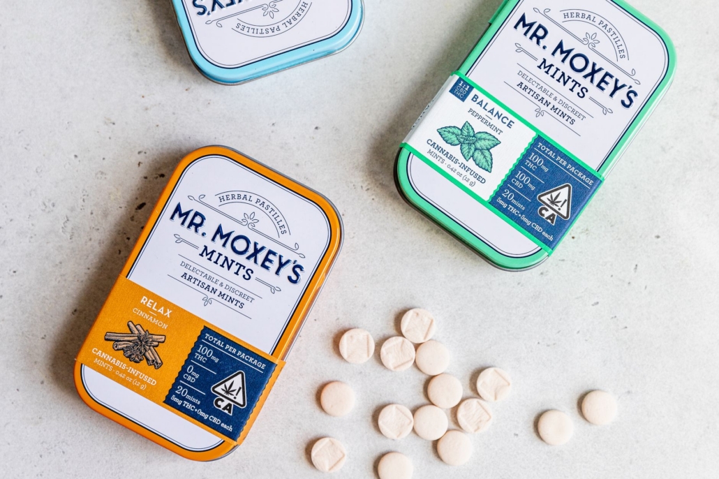 Top view of cannabis-infused artisan mints in colorful tins by Mr. Moxey's, showcasing relaxation and balance.